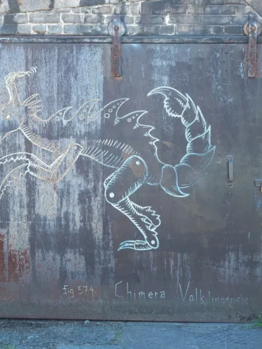 Chimère blanche de Codex Urbanus sur une porte métallique rouillée, avec l'inscription Fig. 574 : Chimera Volklingensis