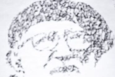 Fresque de JonOne en hommage à l'abbé Pierre, portrait fait de calligraphie noire sur fond blanc