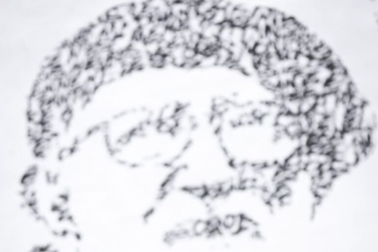 Fresque de JonOne en hommage à l'abbé Pierre, portrait fait de calligraphie noire sur fond blanc
